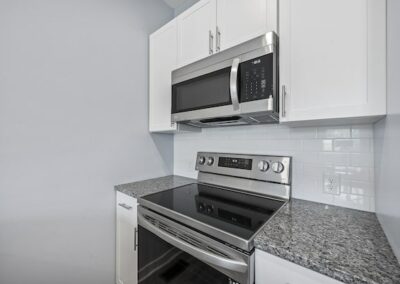 Kitchen with a stainless steel oven, microwave, quartz countertops and white cabinets